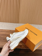 White Louis Vuitton unisex sneaker close-up, lace-up with gold logo patch