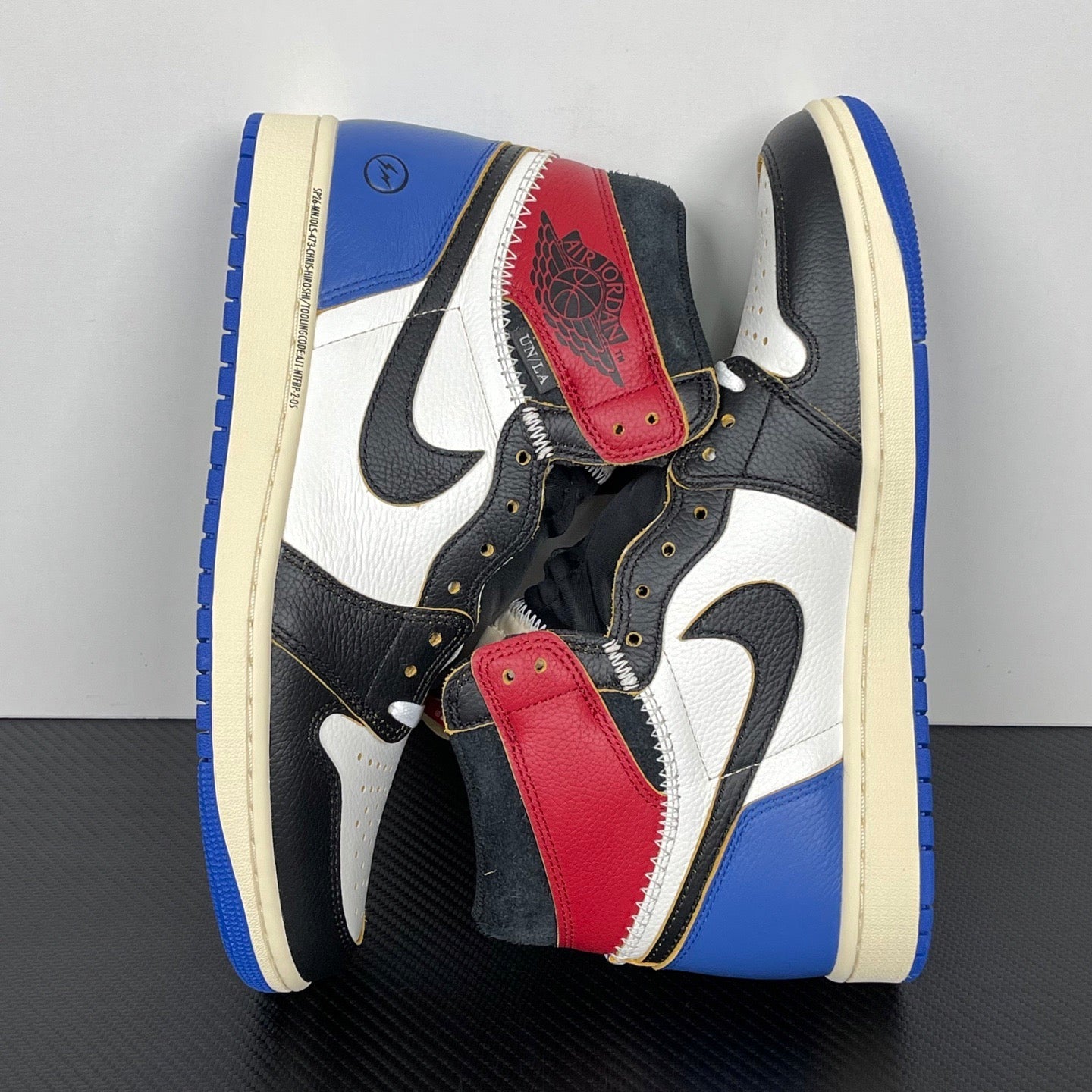 Pair of high-top sneakers angled, black upper with white swooshes, red patches, blue accents