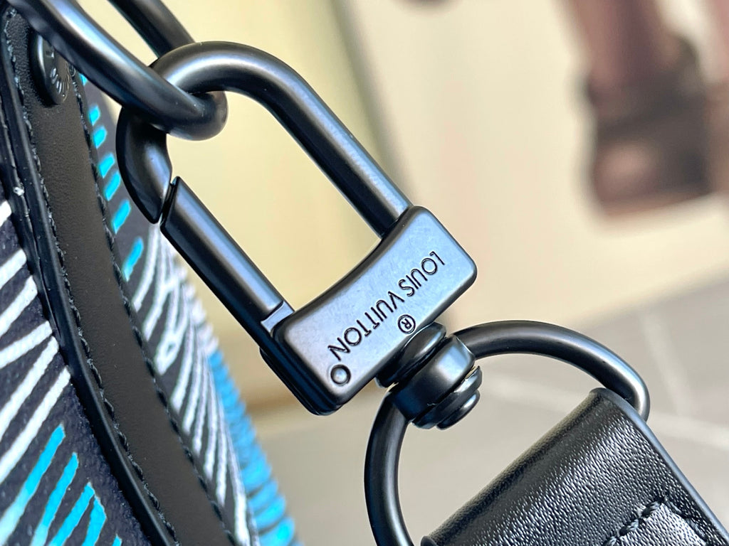 Louis Vuitton duffel bag hardware close-up: black handle rings and small charm tag