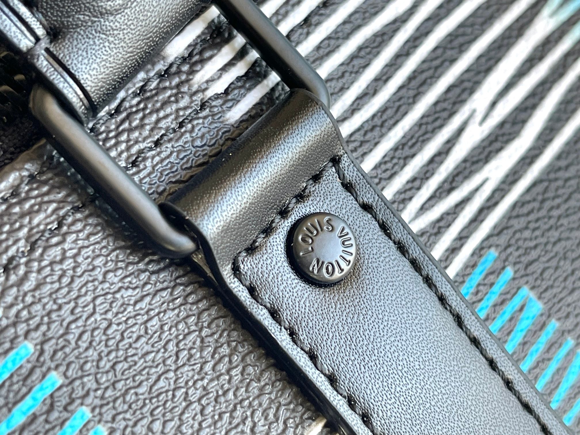 Louis Vuitton duffel bag strap end with stitched leather tab and Louis Vuitton logo stamp