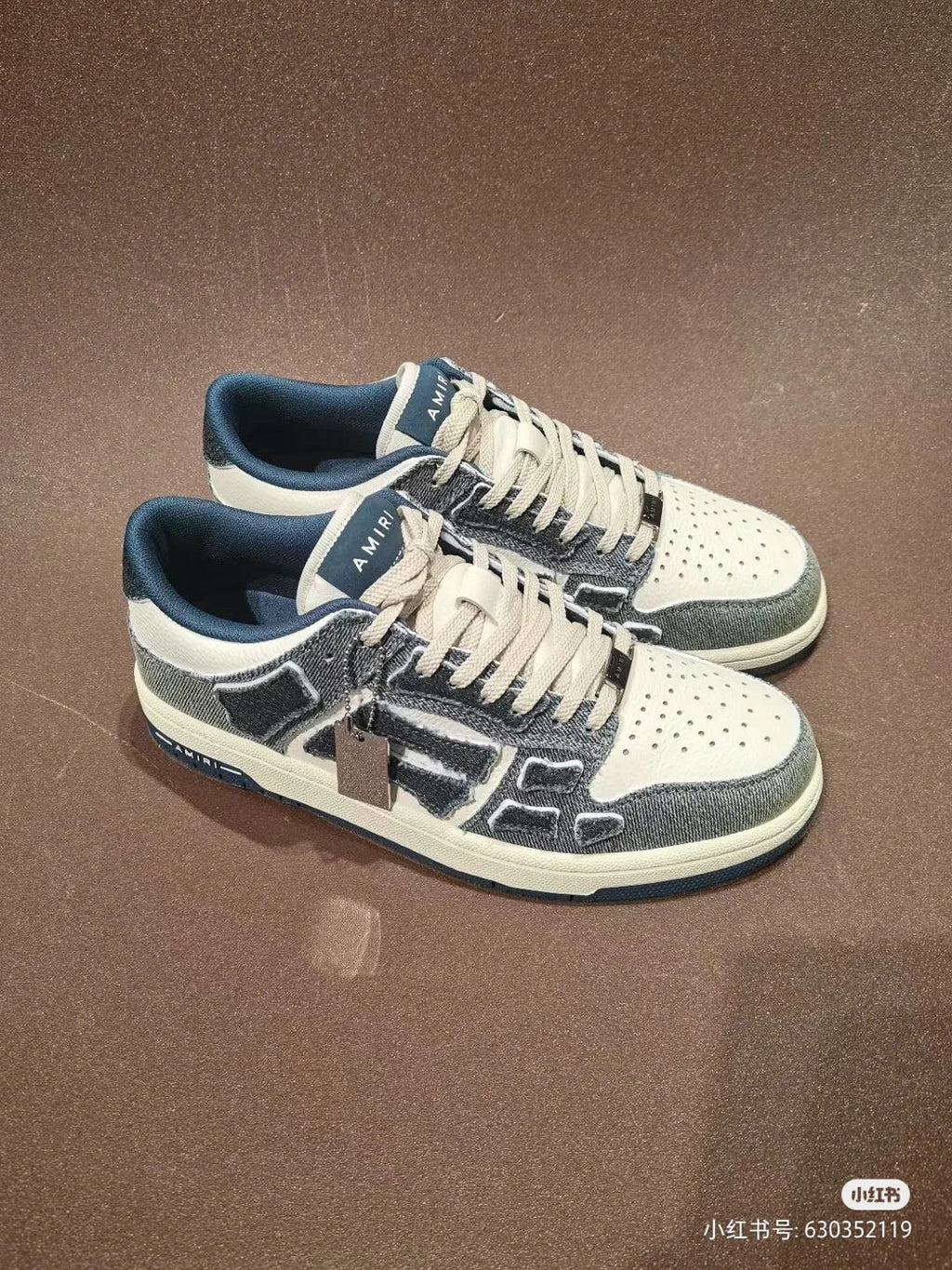 Amiri low-top sneakers pair, white and gray upper with dark blue panels and lace-up
