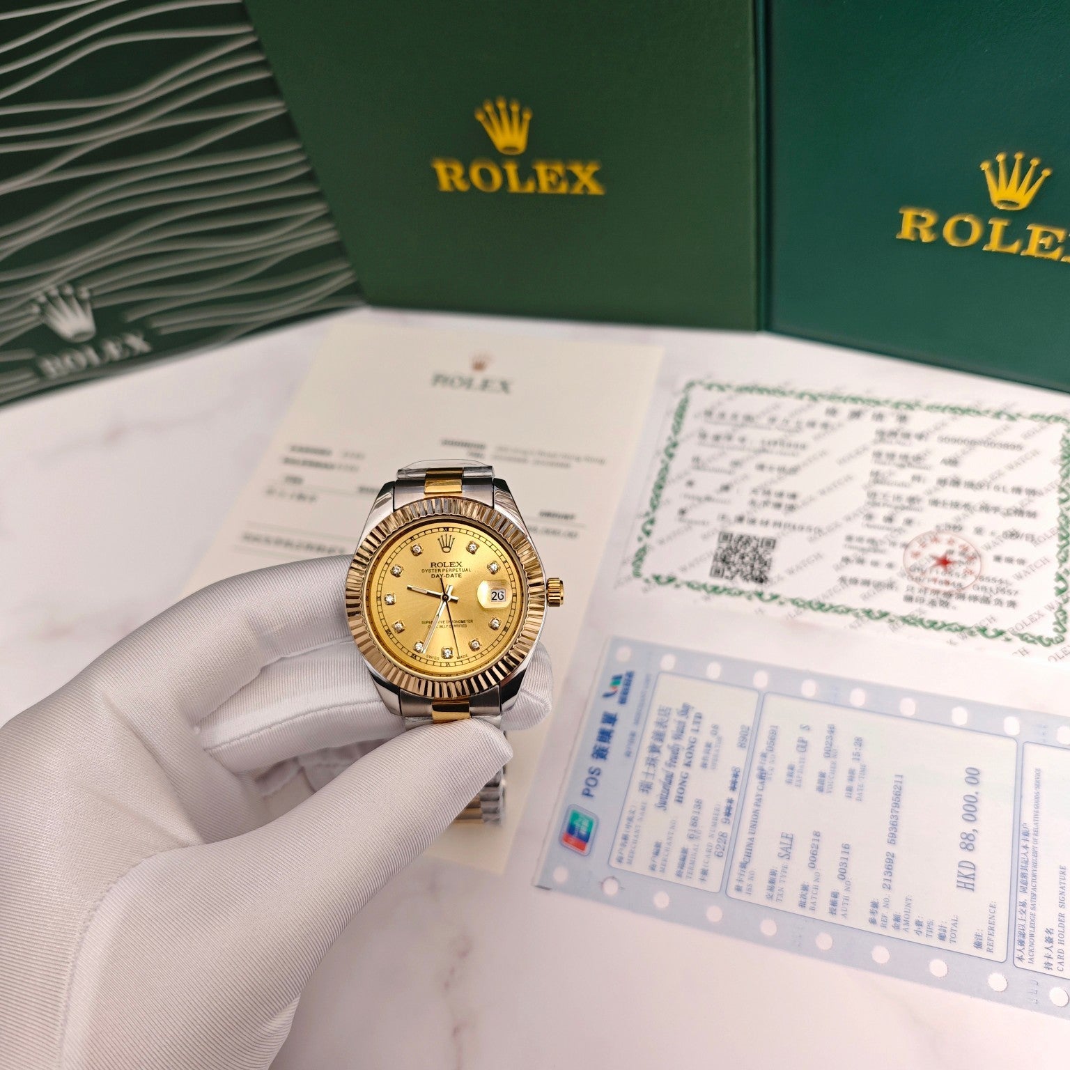 Rolex Day-Date watch on a hand with gold dial, two-tone bracelet, beside paperwork
