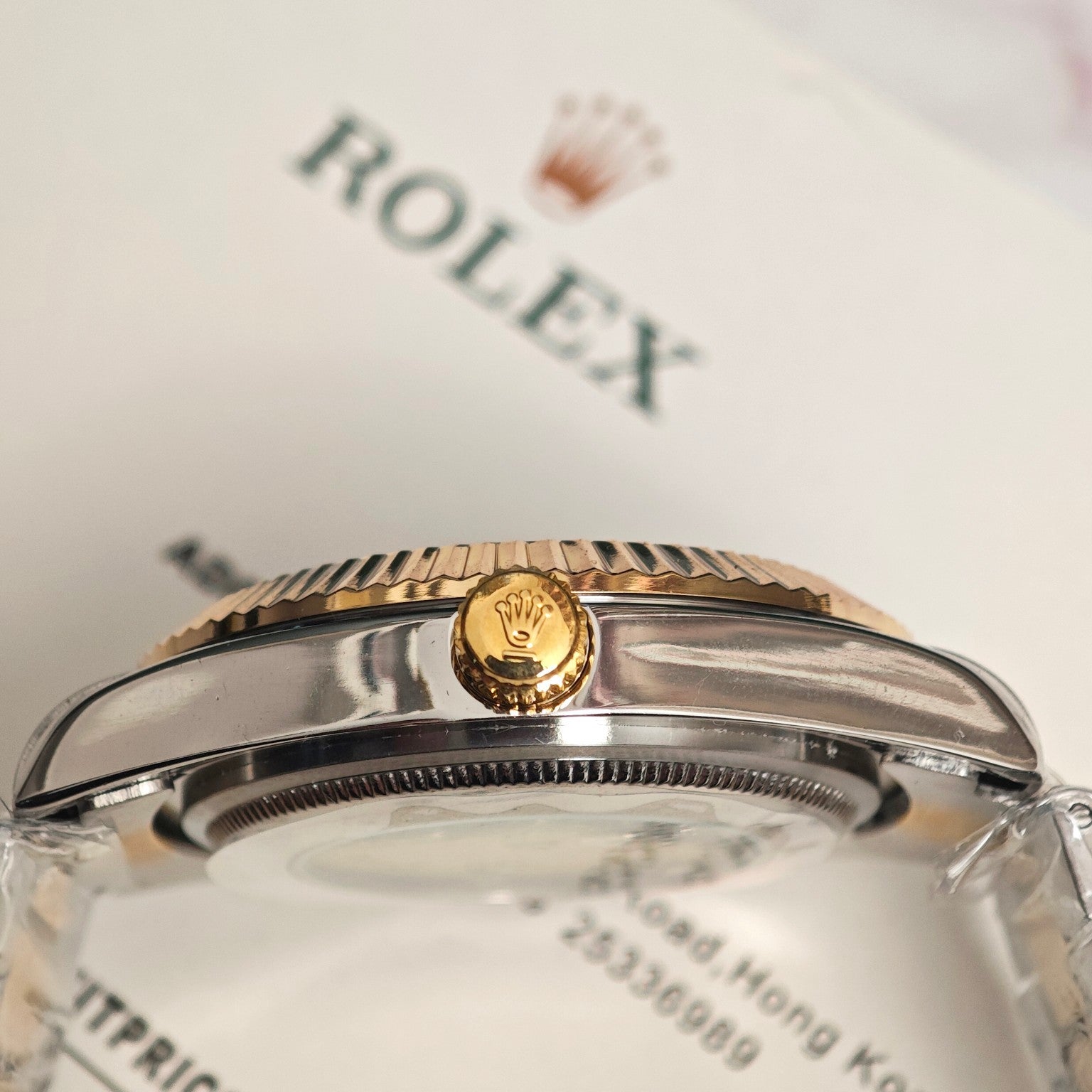 Rolex watch bezel and crown close-up with gold tone accent on clear cover