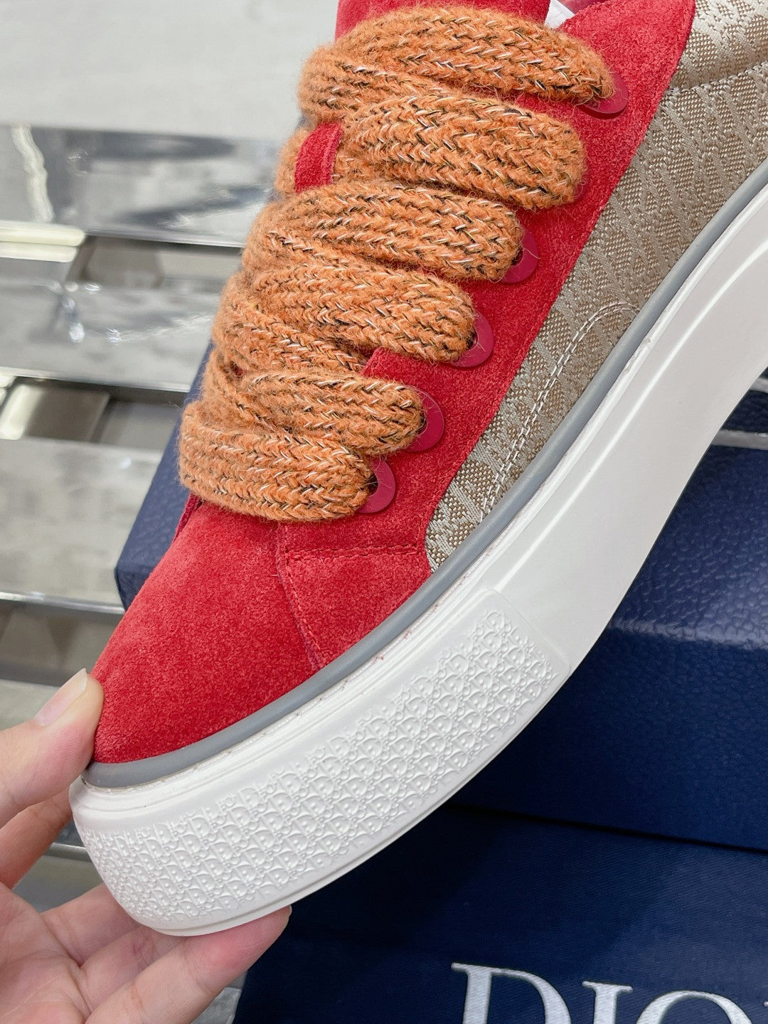 Red suede sneaker close-up with tan rope laces and textured white sole