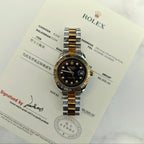Rolex two-tone wristwatch on paperwork, black dial with gold hour markers and hands