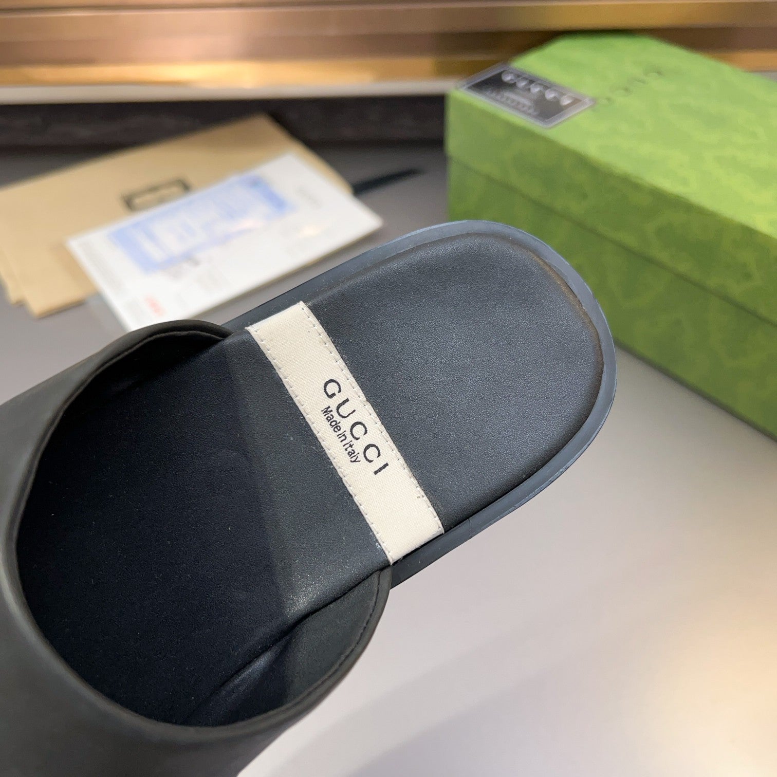 Gucci black leather mule sandal heel view with white logo tag on footbed