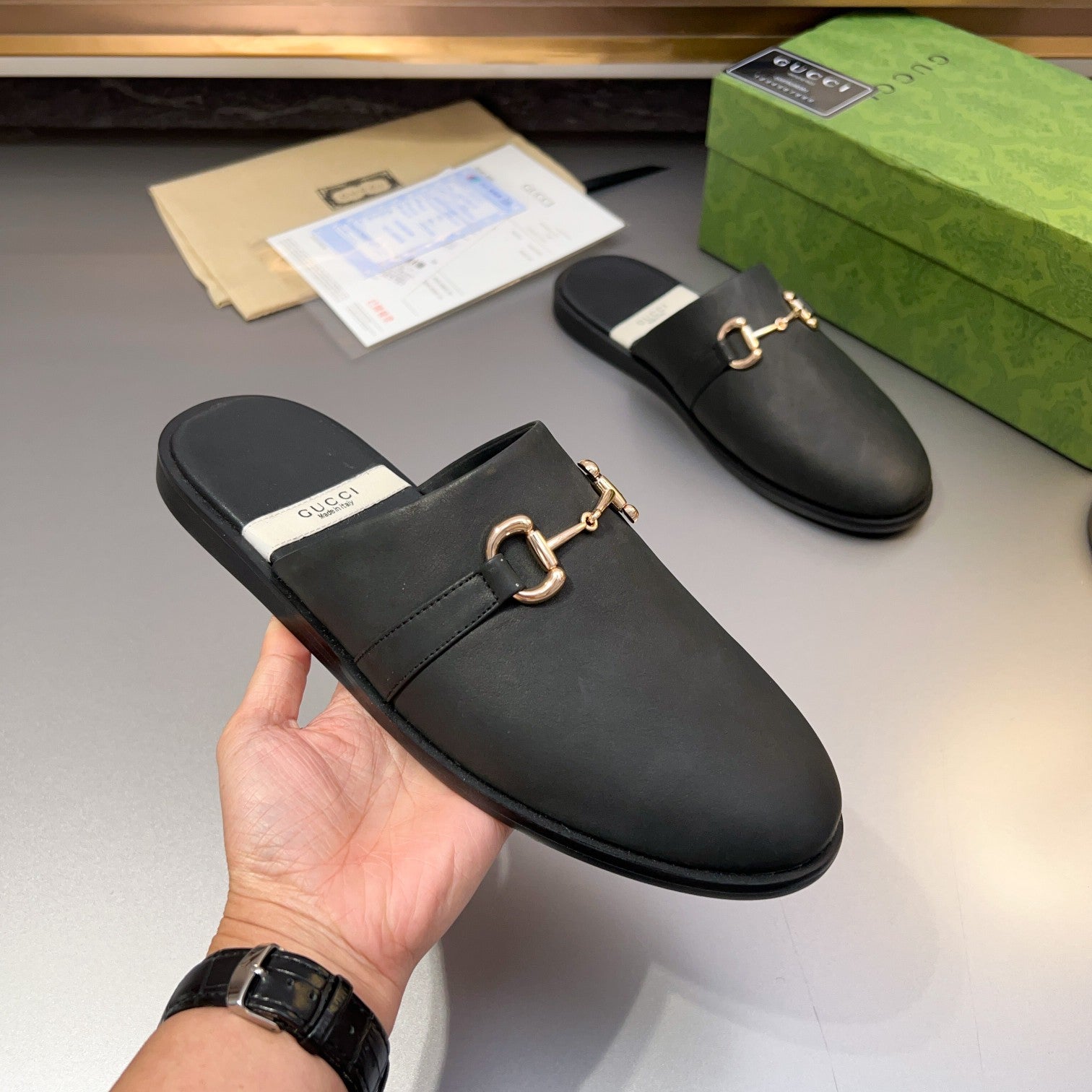 Gucci black leather mule sandal, front view with gold-tone buckle bar and low profile