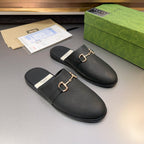 Gucci black leather mule sandals with gold-tone buckle detail on strap and logo footbed