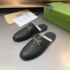 Gucci black leather mule sandals, angled view showing gold-tone buckle and padded sole