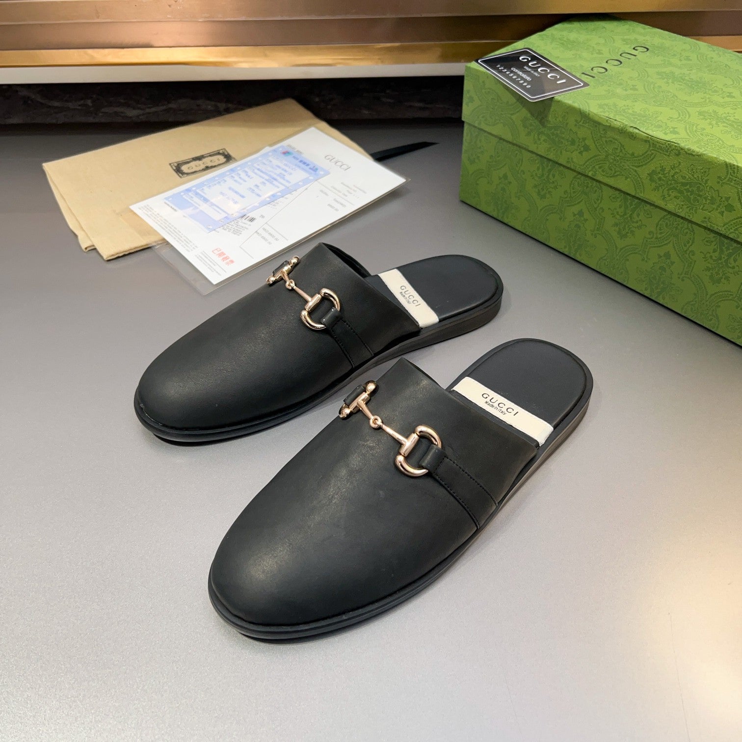 Gucci black leather mule sandals, angled view showing gold-tone buckle and padded sole