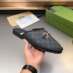 Gucci GG patterned slide sandal held in hand, gold-tone horsebit hardware and dark upper