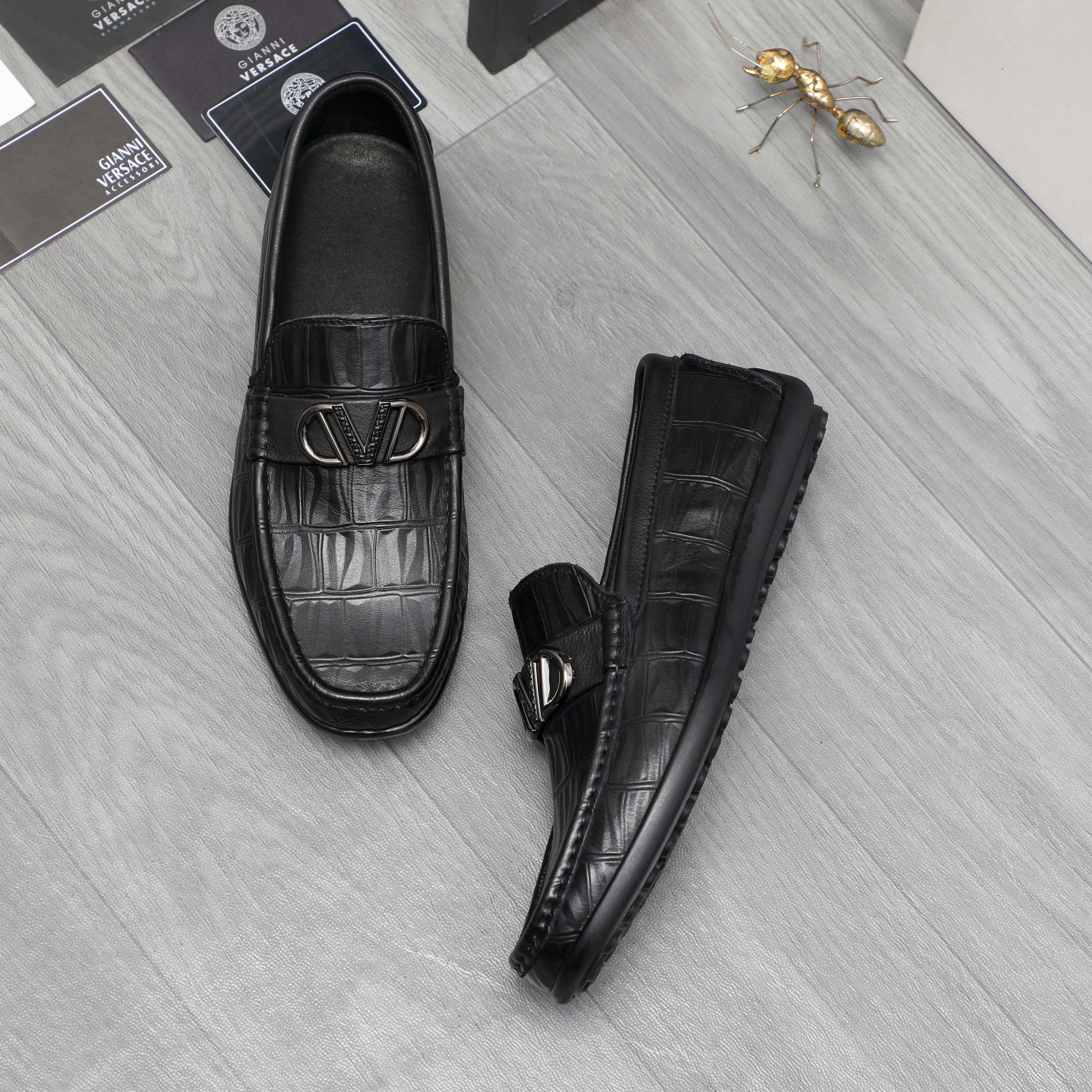 Black leather loafers with embossed texture and metal buckle, side and front view
