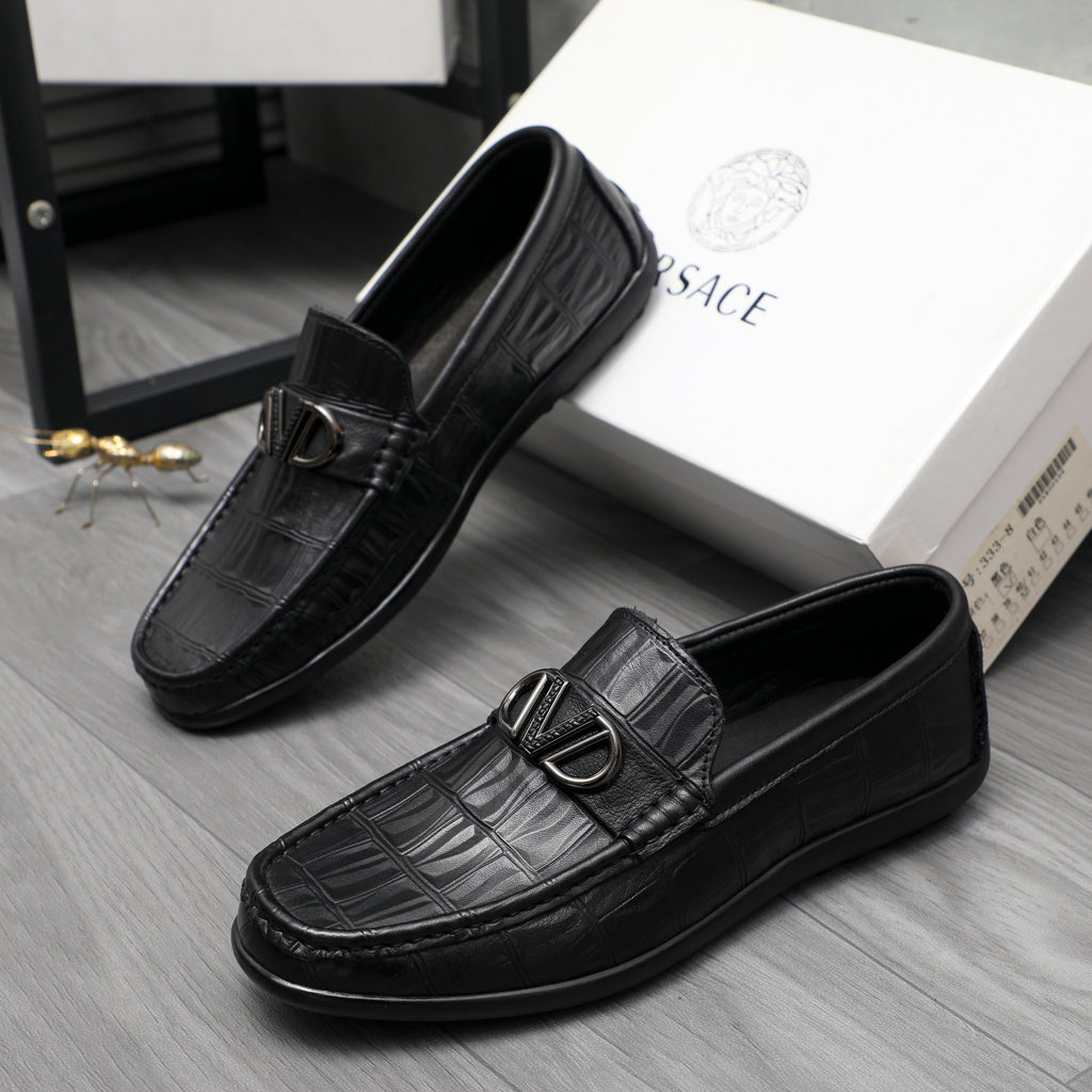 Black leather loafers with embossed texture and metal buckle, angled view