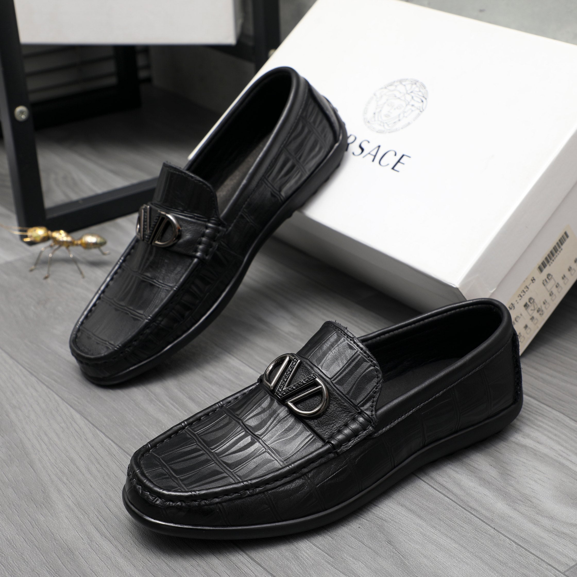 Black leather loafers with embossed texture and metal buckle, angled view