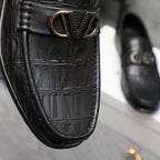 Close-up of black embossed leather loafer with V-shaped metal buckle