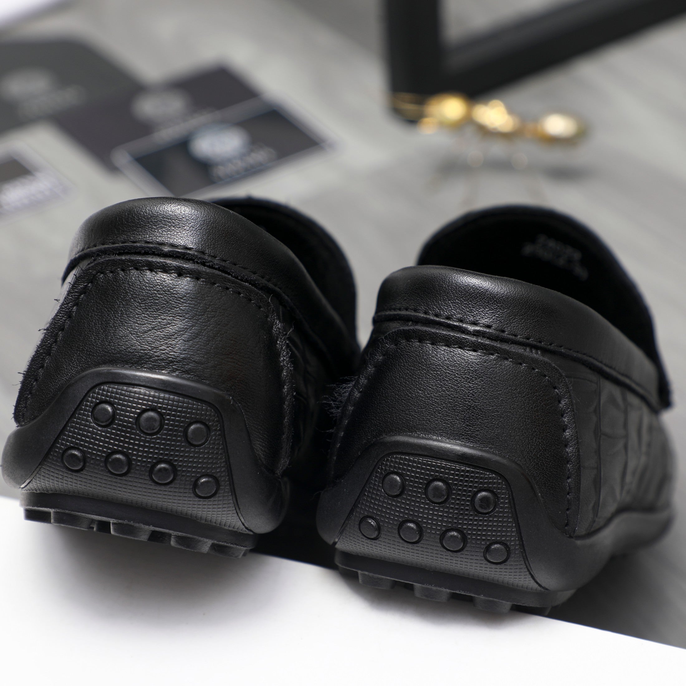 Pair of black loafers showing rounded outsole with stud tread