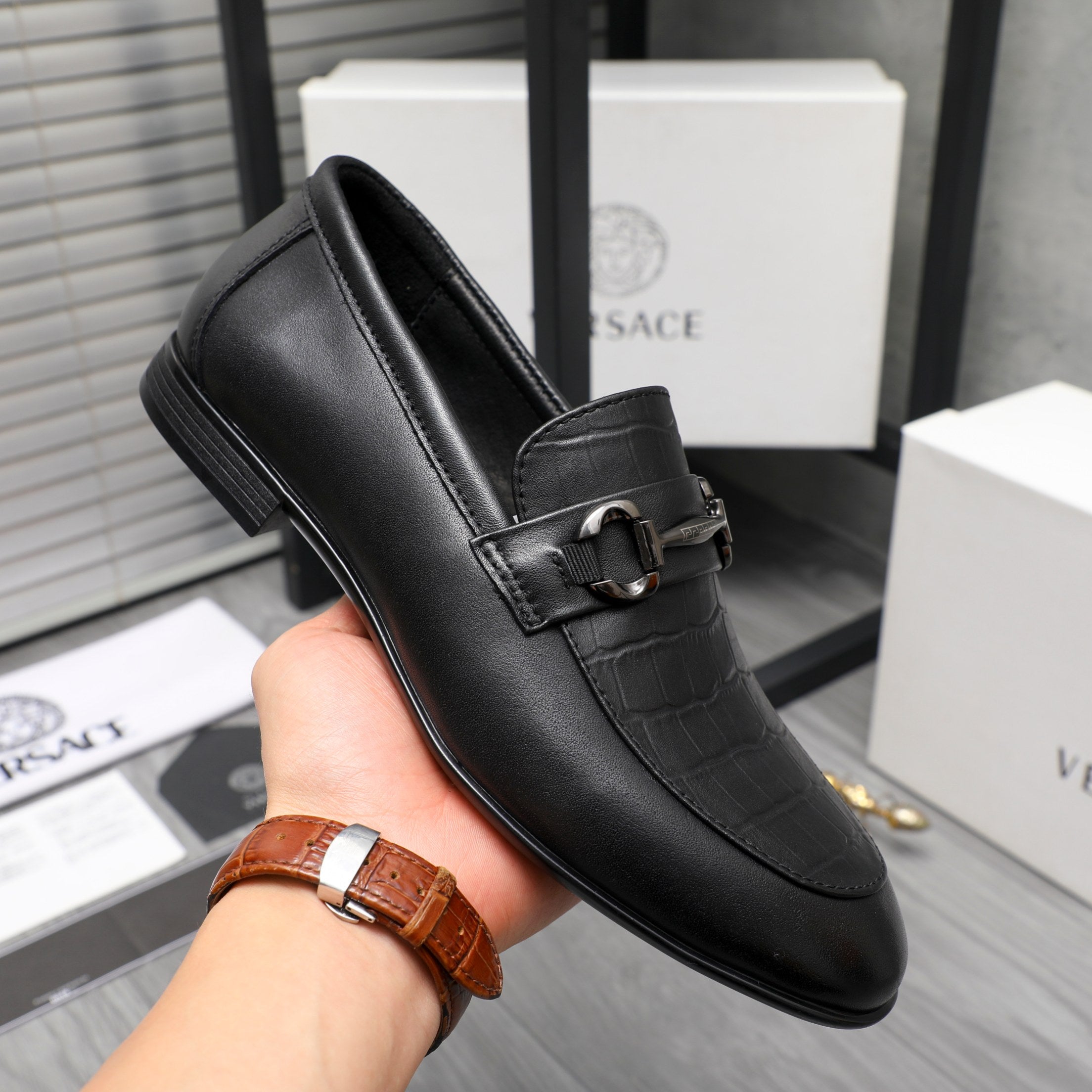 Black leather loafer with strap buckle, low heel, and smooth upper