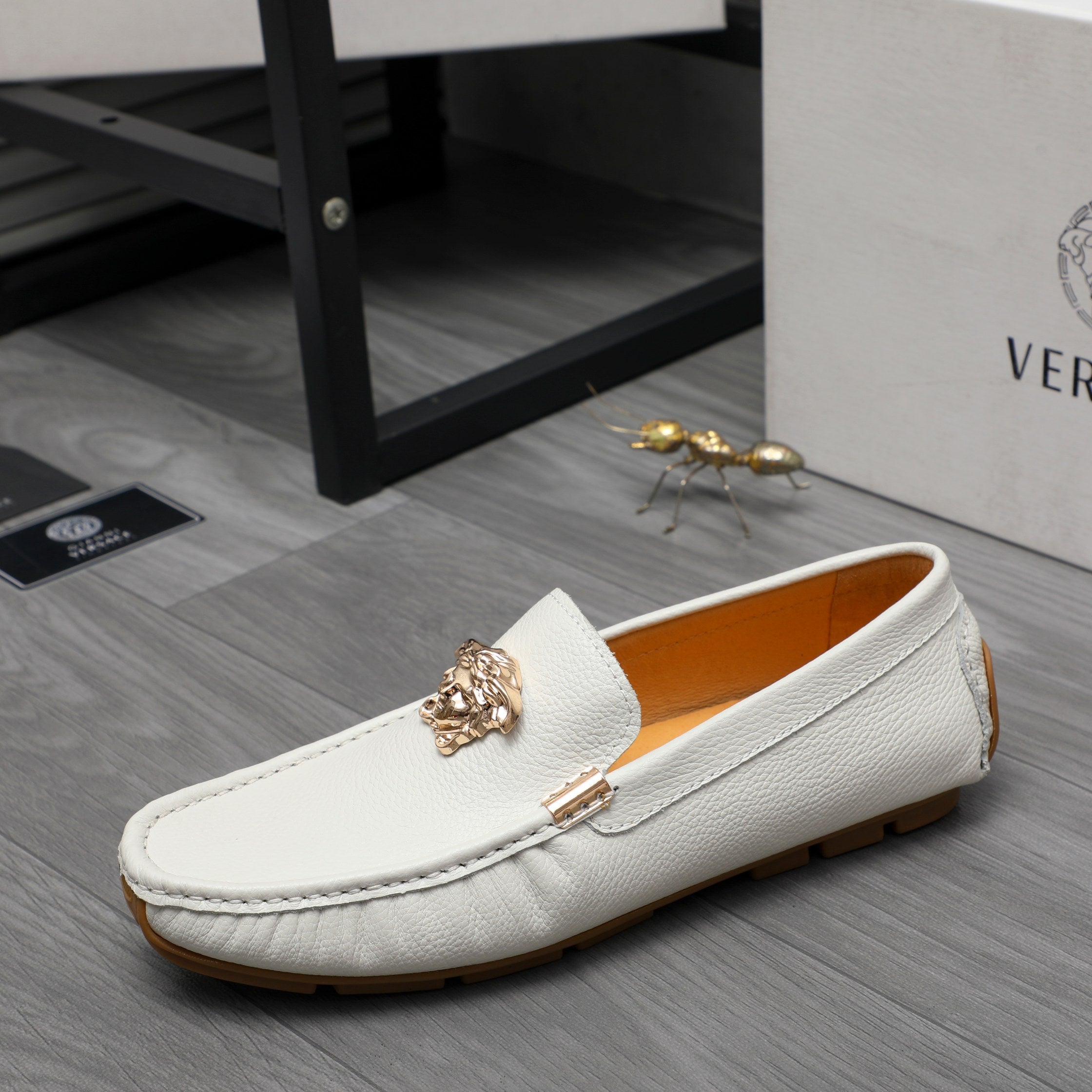 White leather loafer with gold emblem and metal bar, low-profile sole