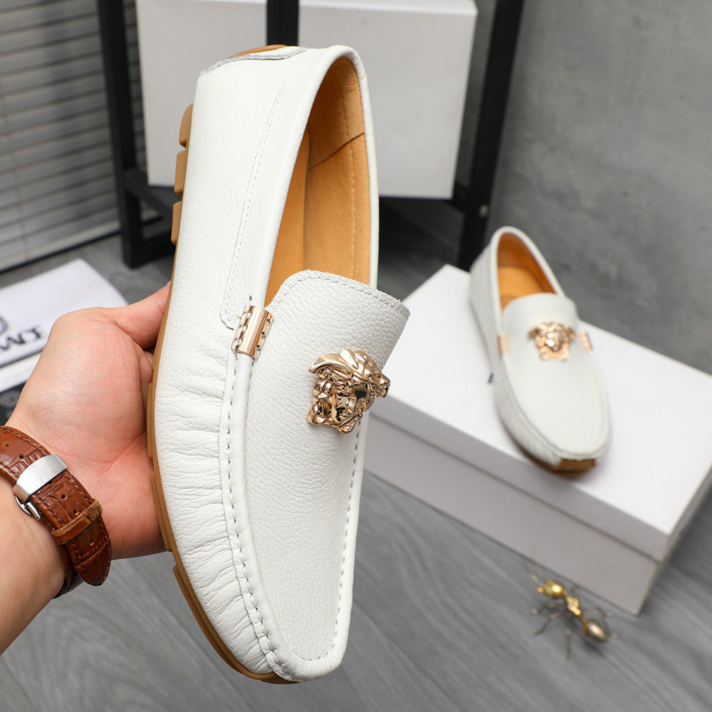 White leather slip-on loafer with gold emblem detail, hand holding