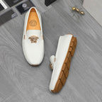 White leather loafers with gold emblem and brown tread sole, side view