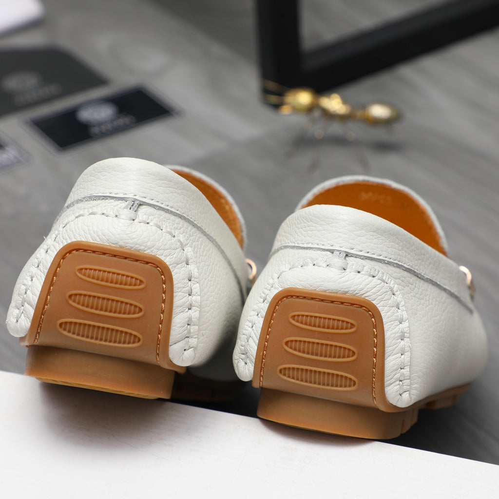 Pair of white loafers showing brown rubber outsoles with ridged tread