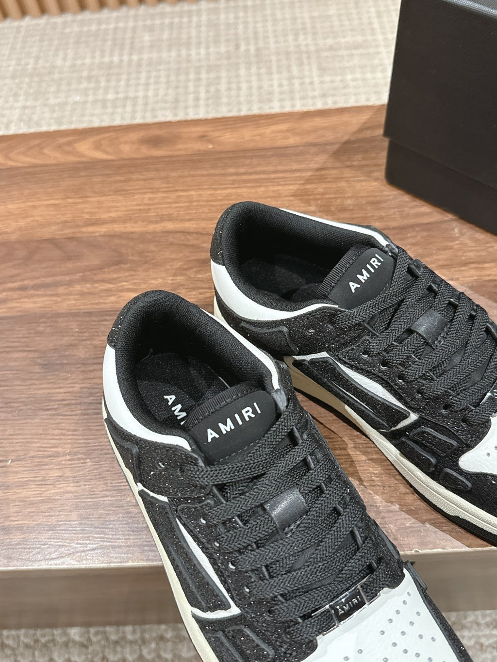 Amiri low-top sneakers close view, black glitter texture, white side stripes, lace-up