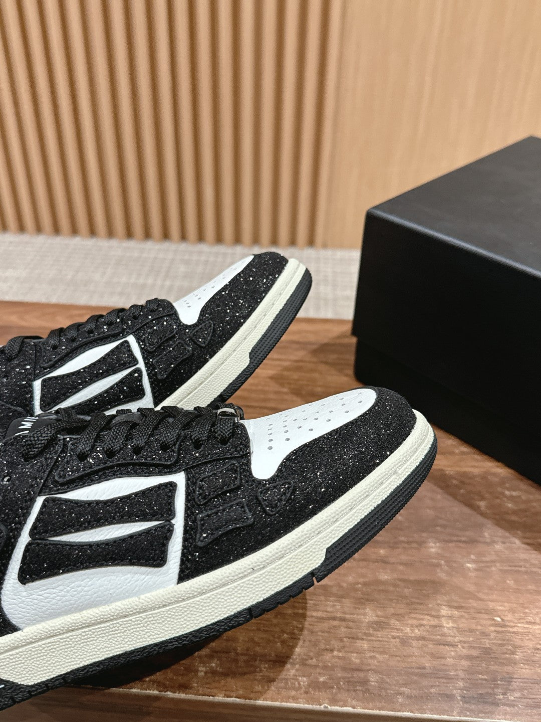 Amiri low-top sneakers close-up, black glitter with white panels, black laces