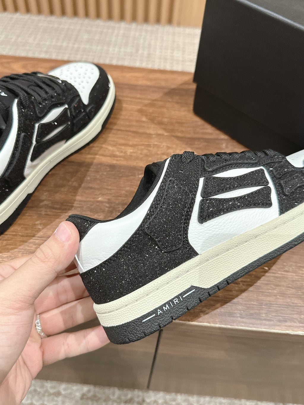 Amiri sneaker front view, black glitter with white logo panel and toe, lace-up sole