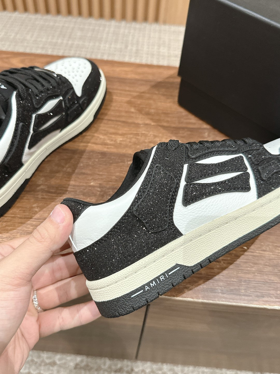 Amiri sneaker front view, black glitter with white logo panel and toe, lace-up sole