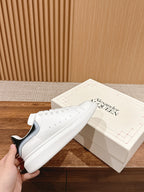 White leather Alexander McQueen sneakers with black heel tab and stud details