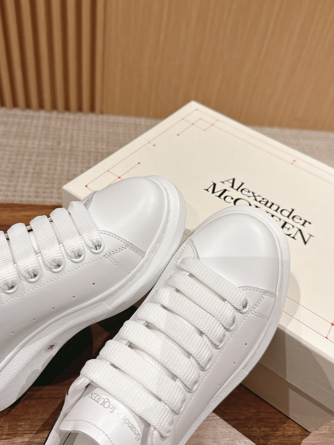 White low-top lace-up sneakers with perforated toe and padded collar