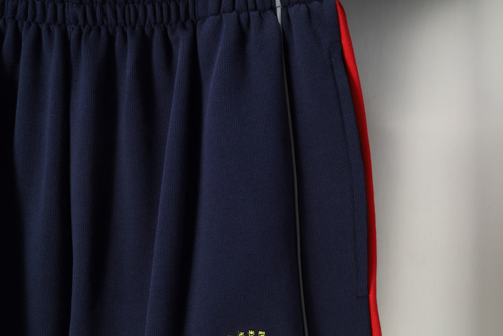 Navy pleated shorts with red side trim and elastic waistband