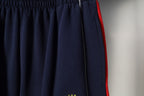 Navy pleated shorts with red side trim and elastic waistband