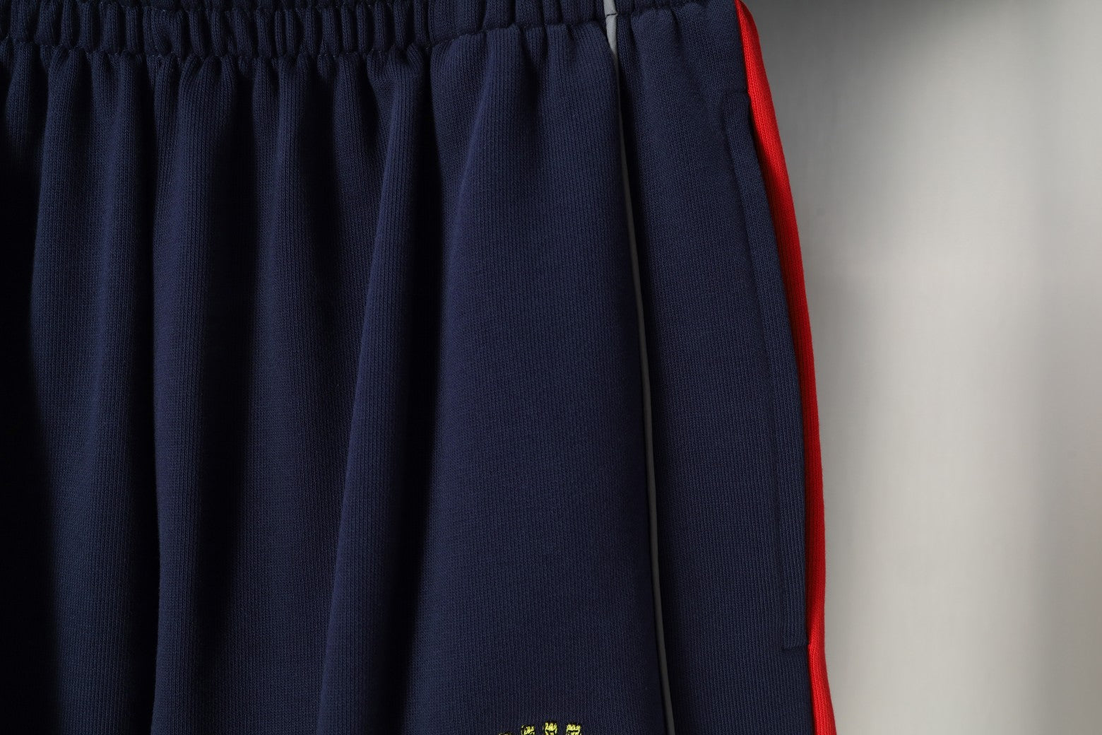 Navy pleated shorts with red side trim and elastic waistband