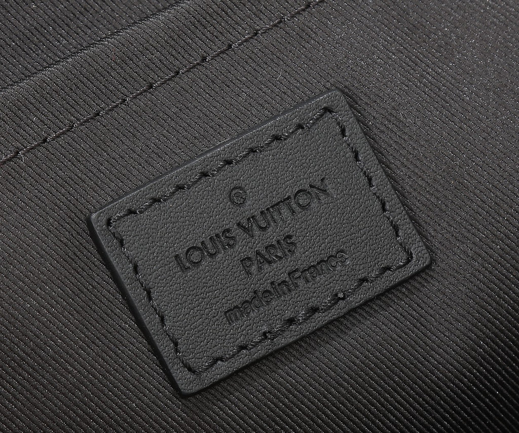 Black leather crossbody bag label patch with embossed Louis Vuitton text