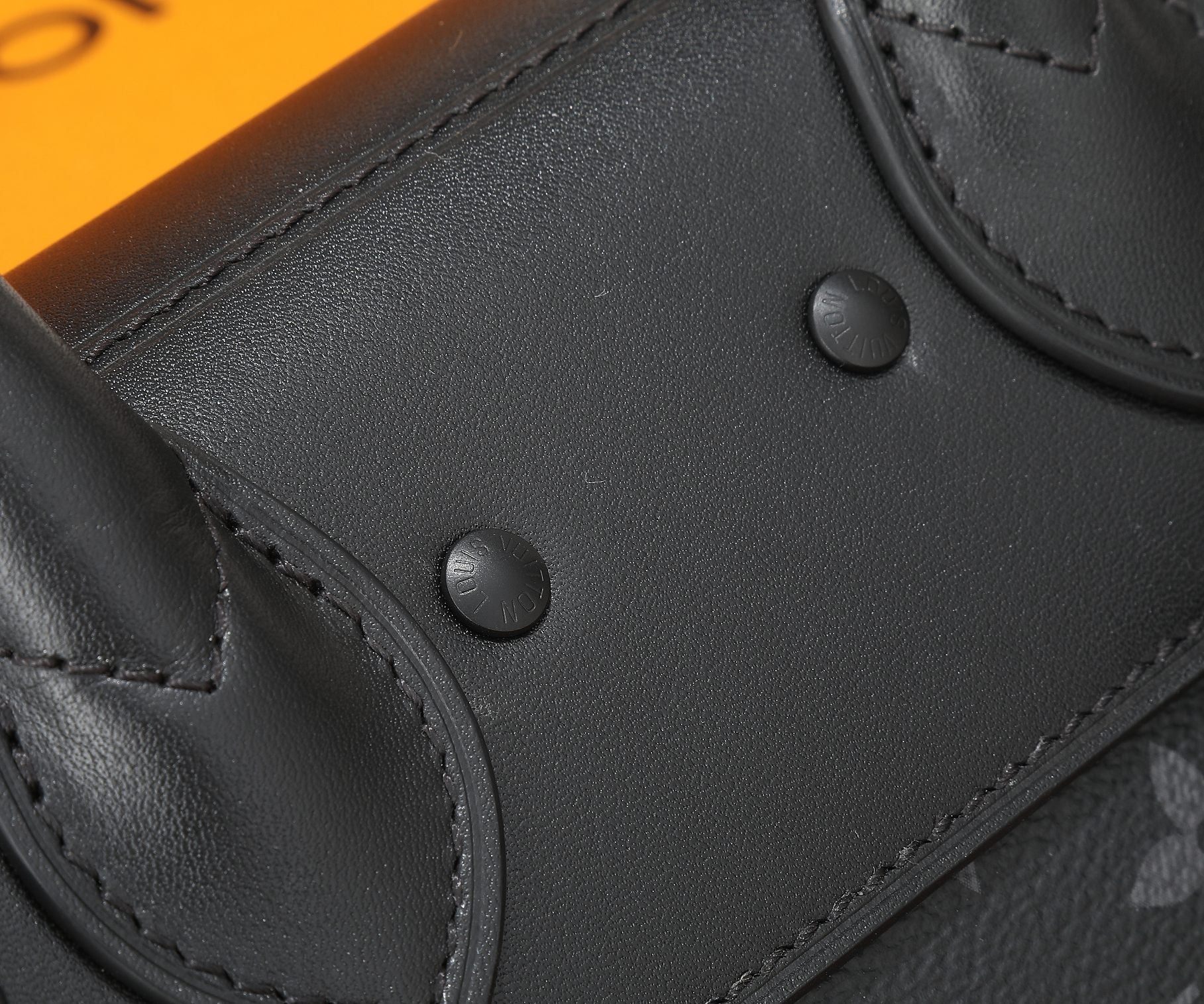 Louis Vuitton men's bag flap close-up with snap buttons and visible stitching.