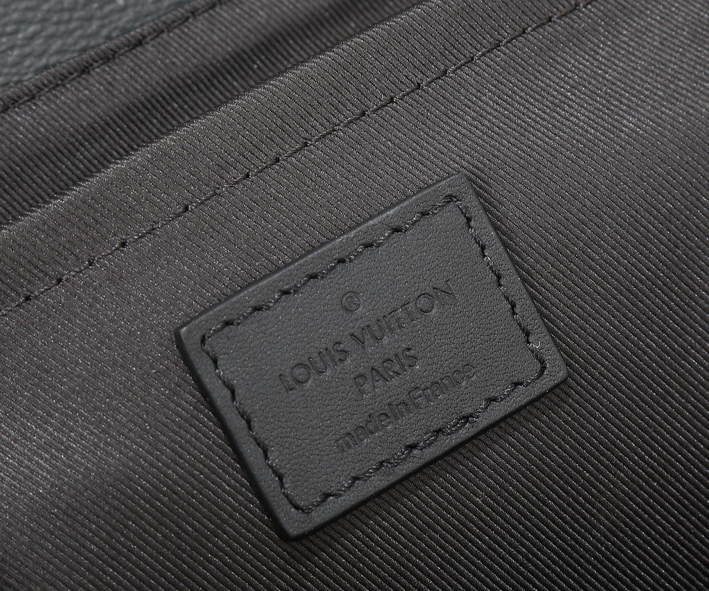 Louis Vuitton men's bag leather brand tag close-up on dark textured panel.