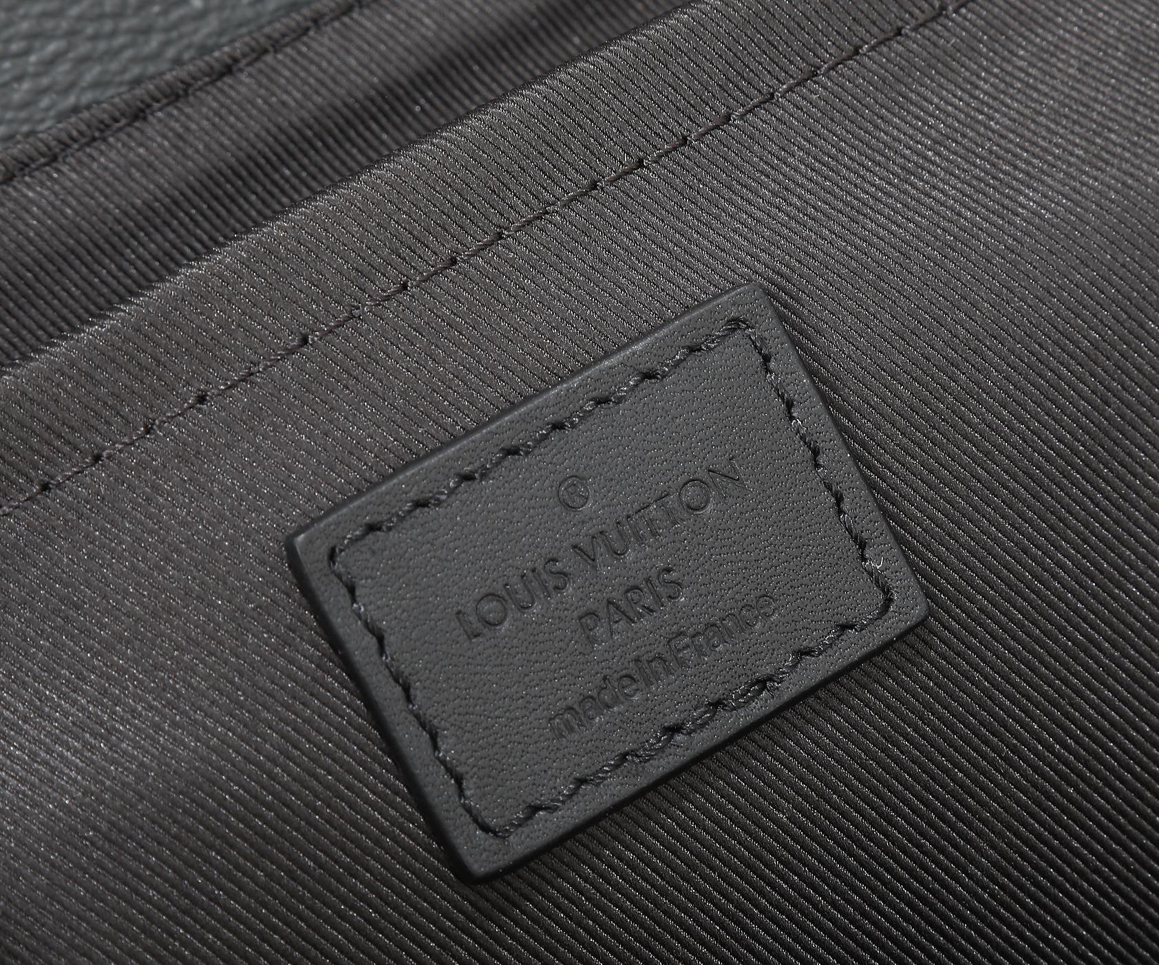 Louis Vuitton men's bag leather brand tag close-up on dark textured panel.