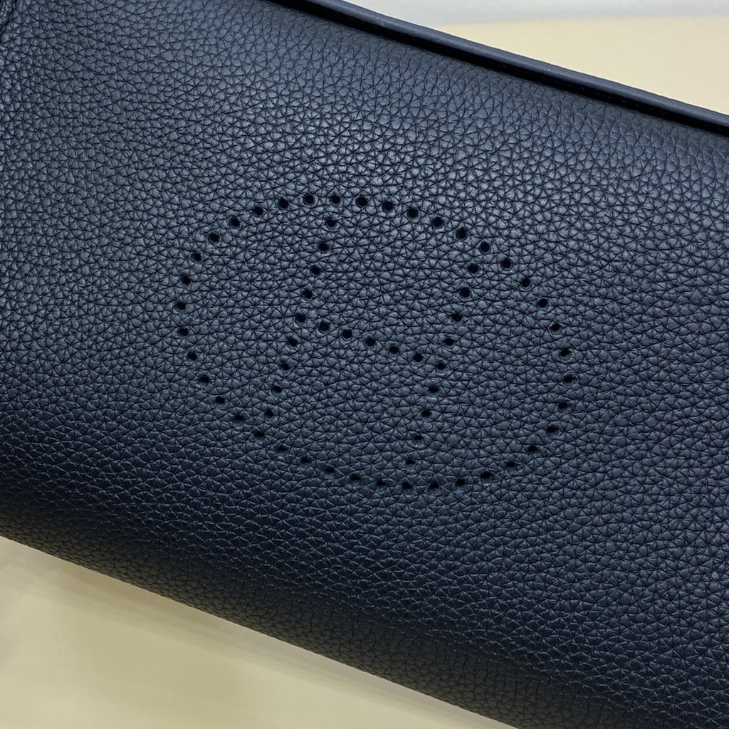 Hermes bag close-up of dark blue pebbled leather with stitched logo motif.