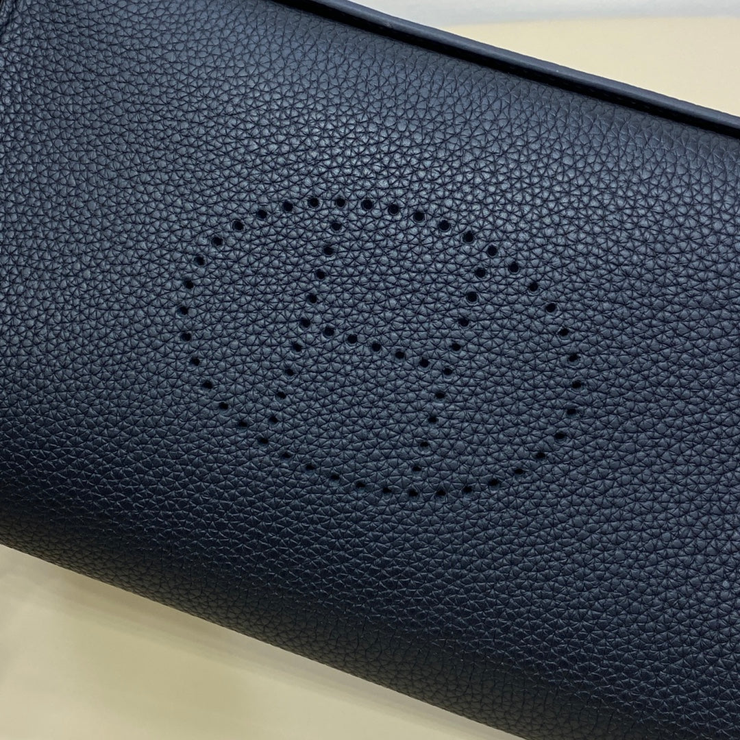 Hermes bag close-up of dark blue pebbled leather with stitched logo motif.