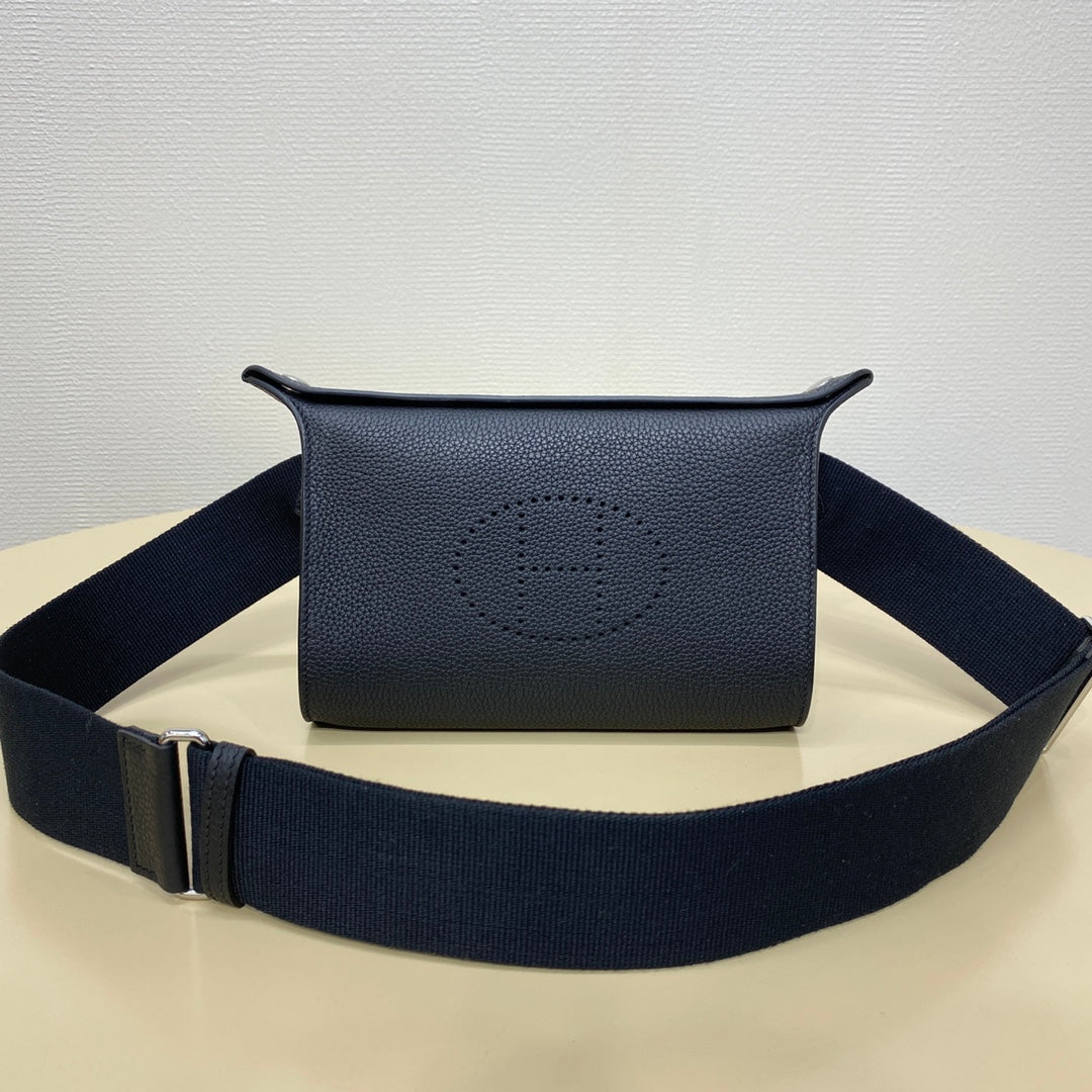 Hermes crossbody bag in dark blue leather with front logo and wide strap.
