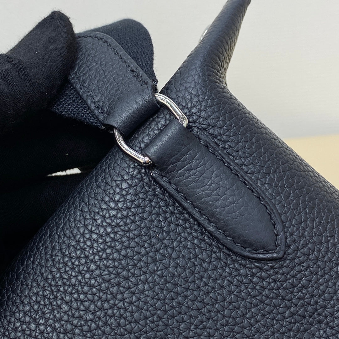 Hermes bag close-up of dark blue leather with strap attachment and silver-tone buckle.