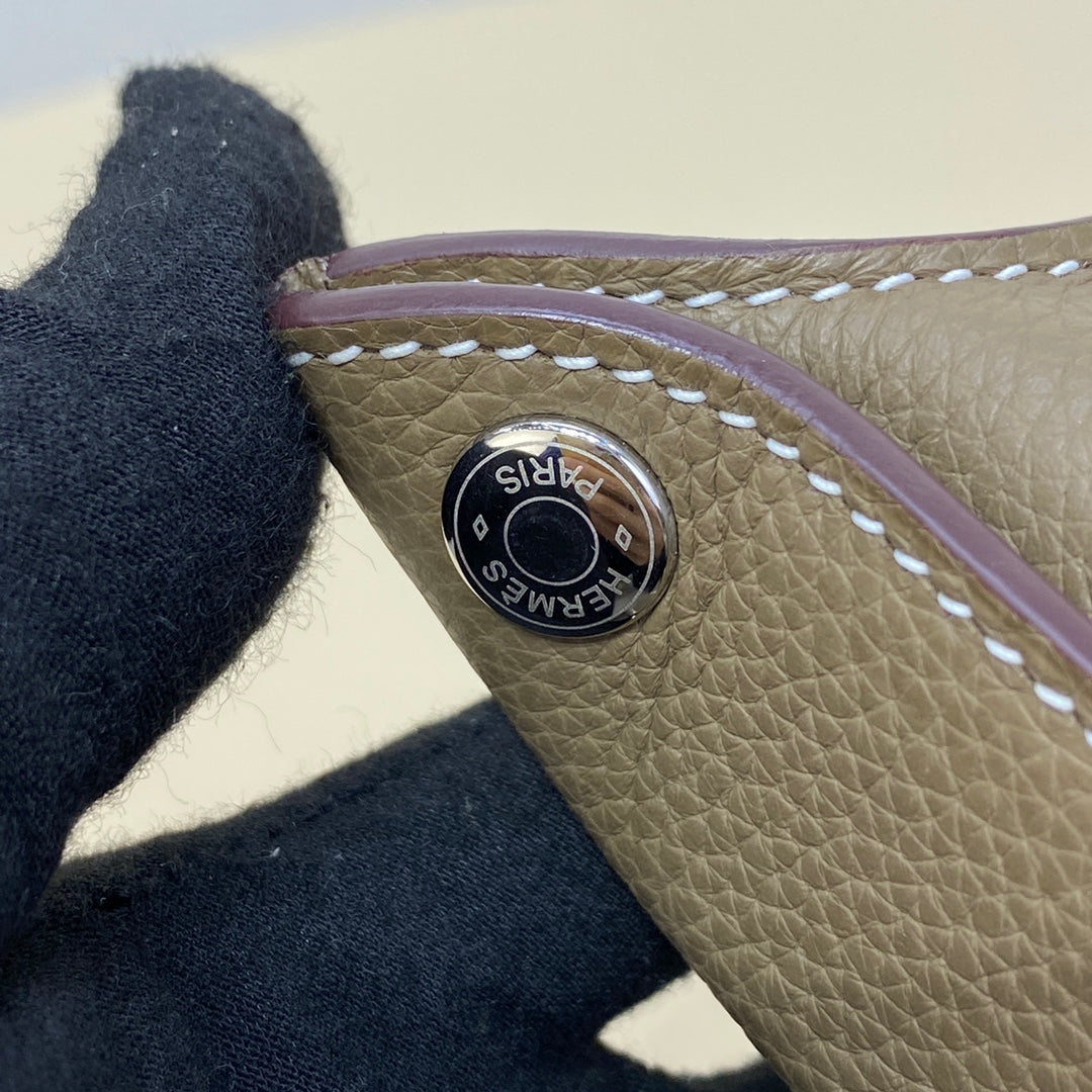 Hermes crossbody bag close-up of round silver snap button with brand text