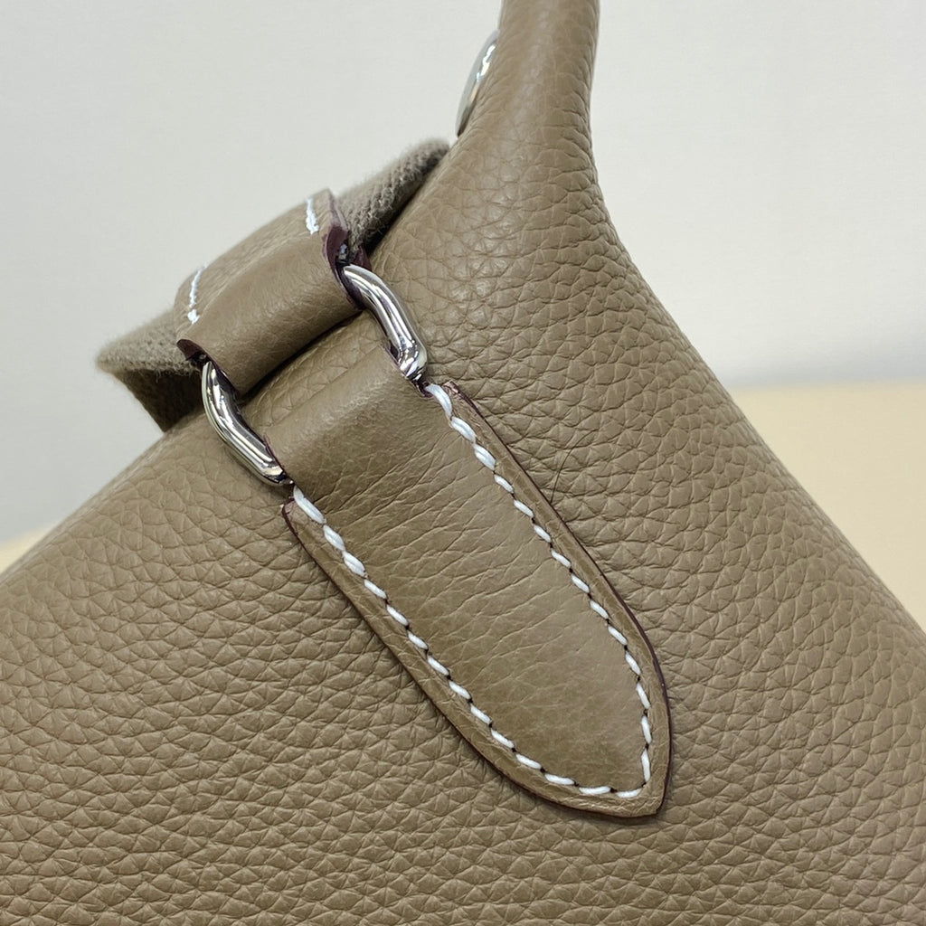 Hermes crossbody bag side detail with silver rings, strap attachment, and contrast stitching
