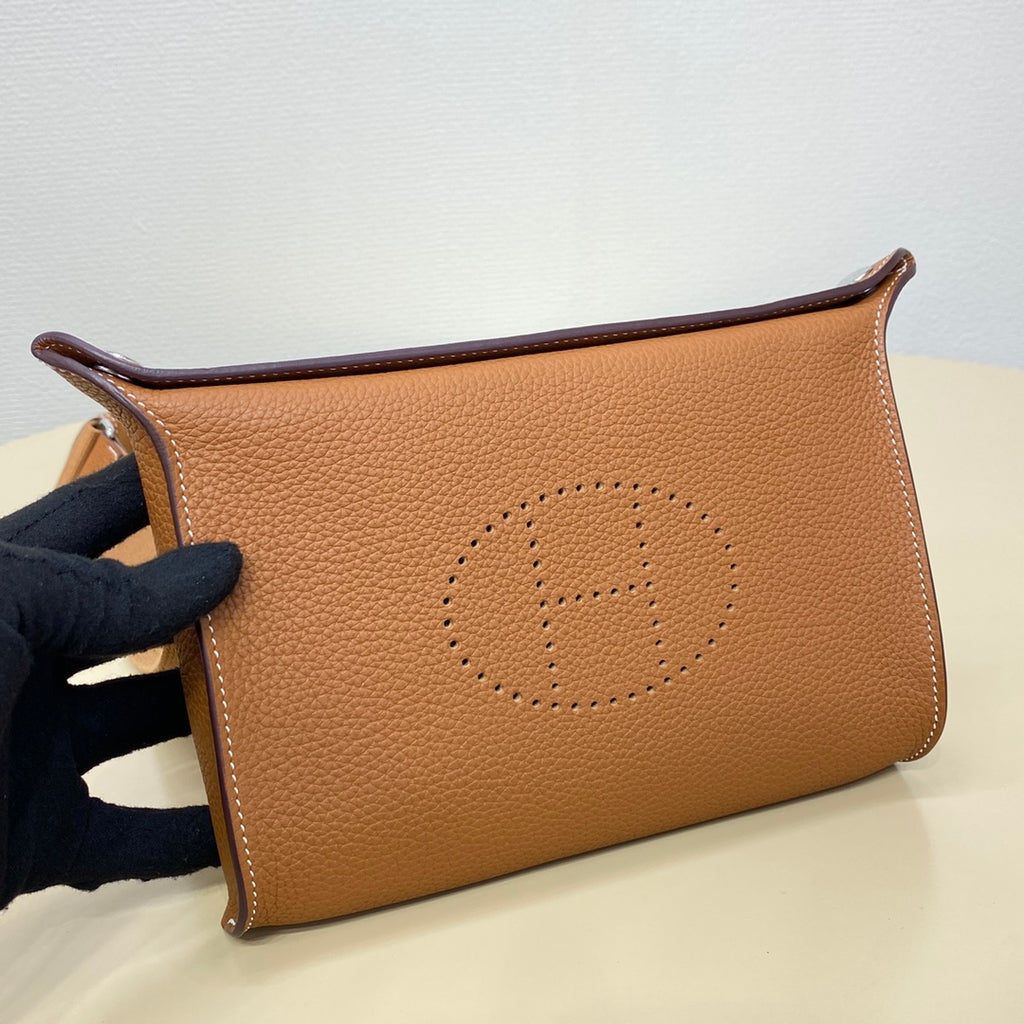 Hermes clutch-style bag in tan leather with stitched logo medallion, side close-up
