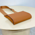 Hermes bag angled view with tan leather body and top handle, dark trim detail