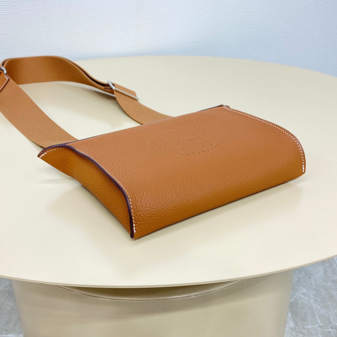 Hermes bag angled view with tan leather body and top handle, dark trim detail