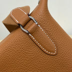 Hermes bag close-up of tan leather strap attachment with metal ring and white stitching
