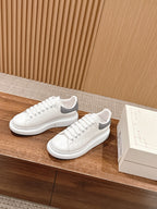 Alexander McQueen white leather sneakers, angled pair on shelf with shoebox