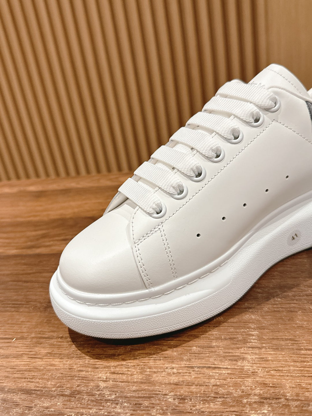 Alexander McQueen white leather sneaker close-up, lace eyelets and textured sole